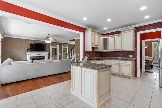 kitchen with cream cabinetry, a sink, gas cooktop, light tile patterned floors, and ornamental molding