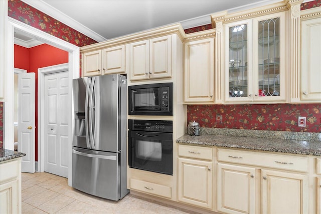 kitchen with black appliances, cream cabinets, wallpapered walls, dark stone countertops, and crown molding