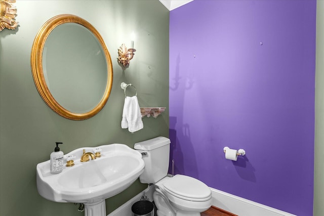 bathroom with a sink, toilet, and baseboards