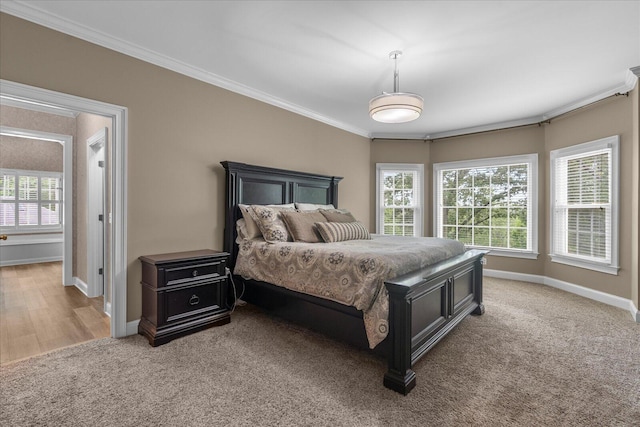bedroom with crown molding, baseboards, and light colored carpet