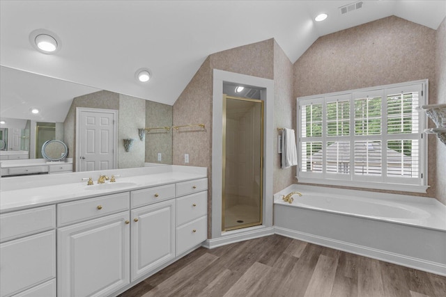 full bath with vaulted ceiling, a stall shower, vanity, wood finished floors, and a bath