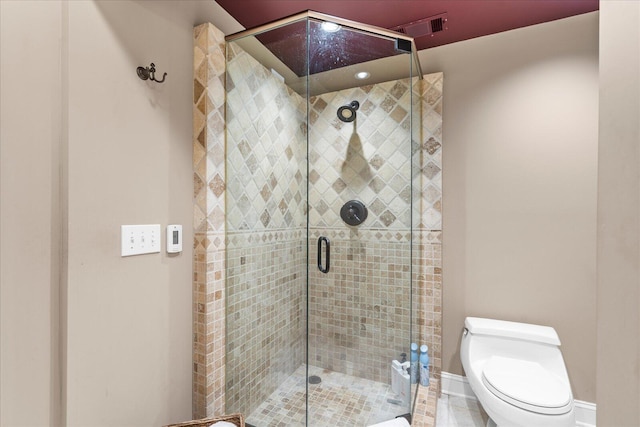 bathroom featuring a stall shower, toilet, and baseboards