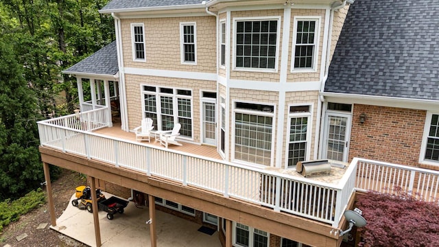 back of house featuring a shingled roof, a wooden deck, and a patio