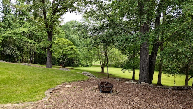 view of green lawn with an outdoor fire pit