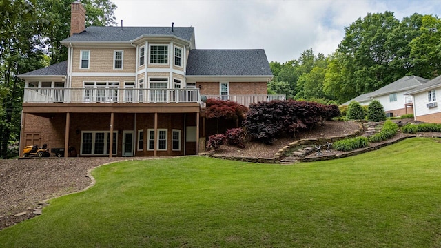 back of property with a chimney, a lawn, a wooden deck, and brick siding