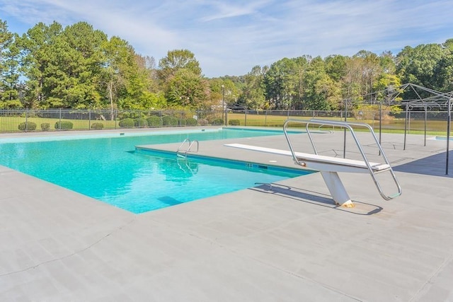 view of pool with fence, a patio area, and a diving board