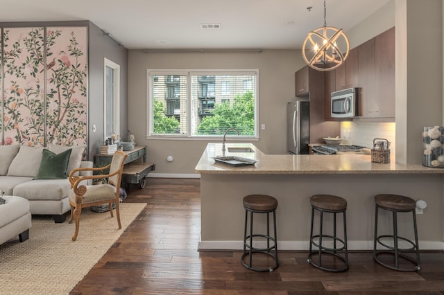 200 Manufacturers Rd Apt 339, Chattanooga, TN 37405 - kitchen featuring stainless steel appliances, a breakfast bar area, dark wood finished floors, tasteful backsplash, and a peninsula