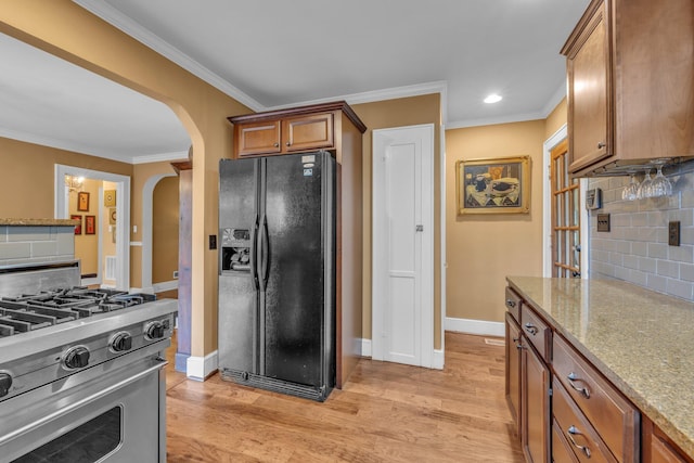 122 Hilltop Dr, Chattanooga, TN 37411 - kitchen with black refrigerator with ice dispenser, stainless steel range, arched walkways, tasteful backsplash, and brown cabinets