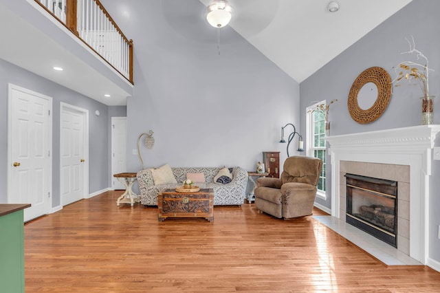 8369 Shadetree Ln, Ooltewah, TN 37363 - living area featuring high vaulted ceiling, a tiled fireplace, light wood-style flooring, ceiling fan, and baseboards