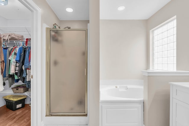 8369 Shadetree Ln, Ooltewah, TN 37363 - bathroom with a shower stall, a bath, a spacious closet, vanity, and wood finished floors