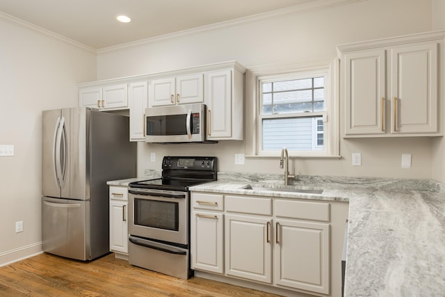 1704 Williams St, Chattanooga, TN 37408 - kitchen with stainless steel appliances, a sink, light wood-type flooring, ornamental molding, and white cabinetry