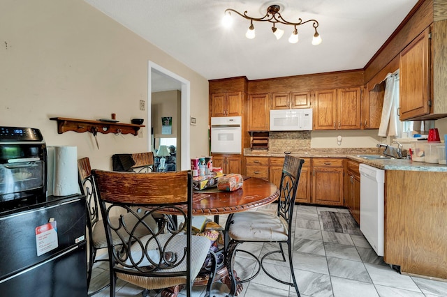 kitchen with white appliances, a sink, brown cabinets, and light marble finish floors