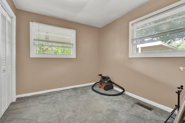unfurnished bedroom featuring multiple windows, carpet flooring, baseboards, and a textured ceiling