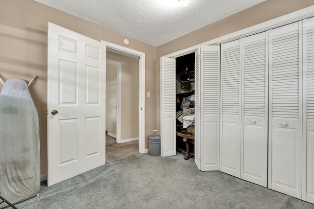 unfurnished bedroom featuring carpet, a closet, a textured ceiling, and baseboards
