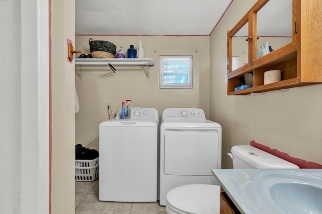 laundry area featuring washing machine and clothes dryer, a textured ceiling, and light tile patterned floors