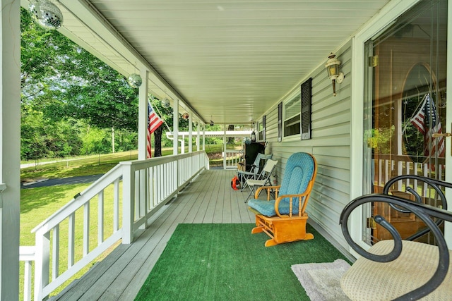 wooden terrace featuring covered porch and a lawn