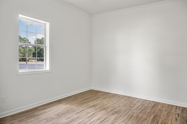 empty room featuring light wood-style flooring, crown molding, and baseboards