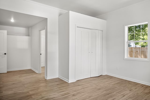unfurnished bedroom with light wood finished floors, a closet, and baseboards