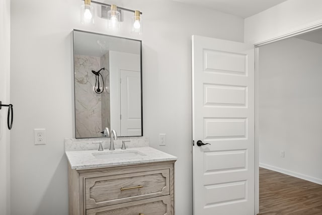 full bathroom featuring vanity, a shower, wood finished floors, and baseboards