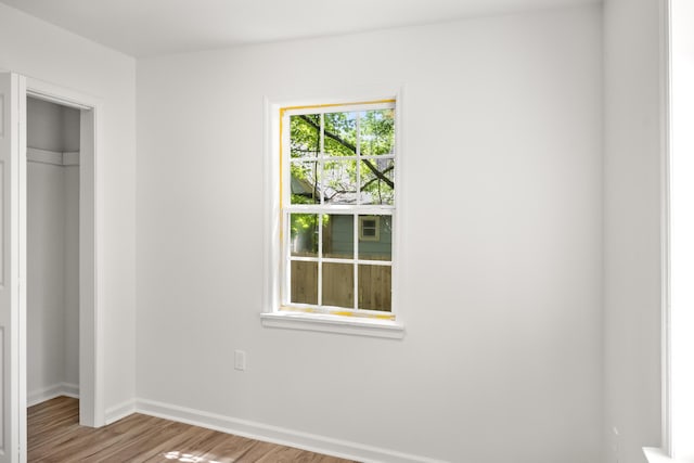 unfurnished bedroom with a closet, wood finished floors, and baseboards
