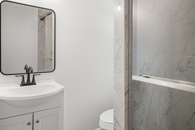 bathroom with toilet, vanity, and a marble finish shower