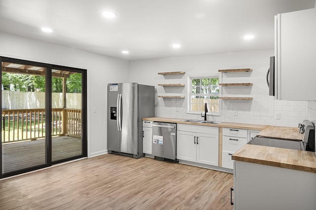 kitchen featuring butcher block counters, stainless steel appliances, a sink, open shelves, and light wood-type flooring