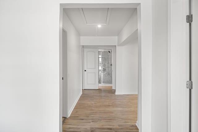 corridor with attic access, wood finished floors, and baseboards