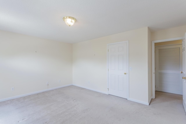 unfurnished bedroom featuring light carpet and baseboards