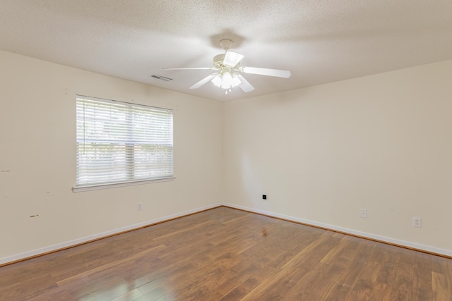 unfurnished room with wood finished floors, ceiling fan, baseboards, and a textured ceiling