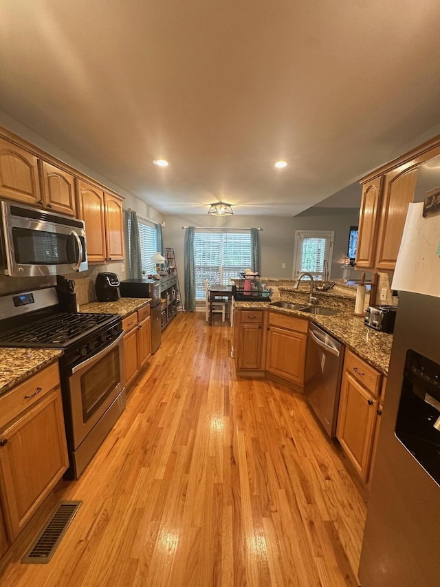 6180 Oilskin Dr, Ooltewah, TN 37363 - kitchen featuring stainless steel appliances, a peninsula, light wood-style floors, dark stone countertops, and recessed lighting