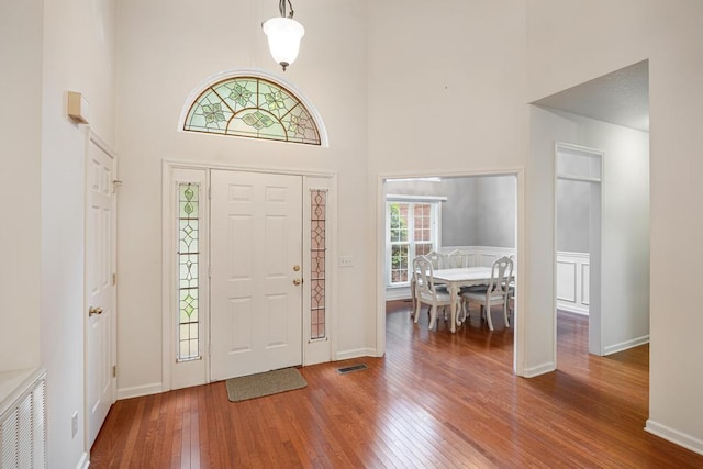 foyer featuring a towering ceiling, wood-type flooring, and baseboards