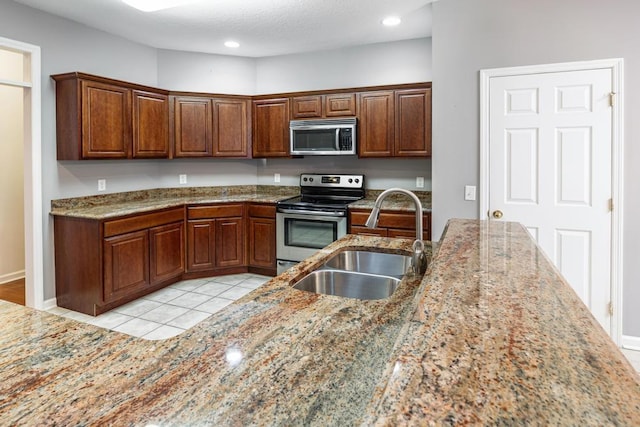 kitchen featuring stainless steel appliances, a sink, recessed lighting, and light stone countertops