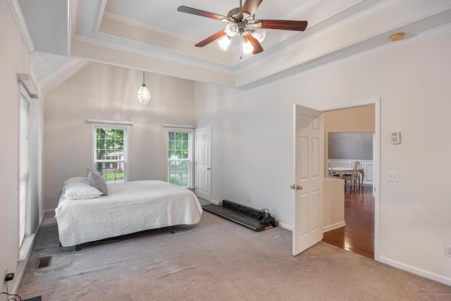 bedroom featuring carpet, ornamental molding, baseboards, a tray ceiling, and ceiling fan