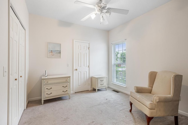 living area featuring light colored carpet, baseboards, and ceiling fan