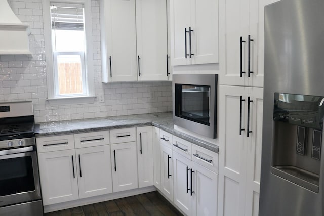 kitchen featuring appliances with stainless steel finishes, white cabinetry, tasteful backsplash, and dark wood-style flooring