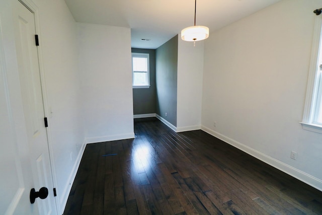 unfurnished room with dark wood-style flooring and baseboards
