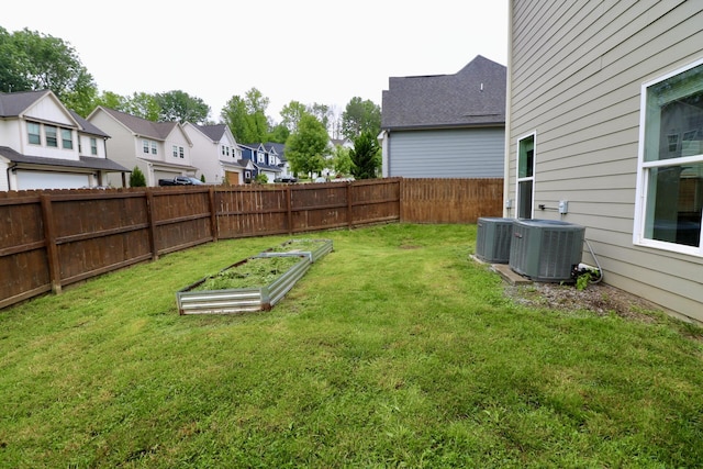 view of yard featuring a garden, a residential view, and central AC