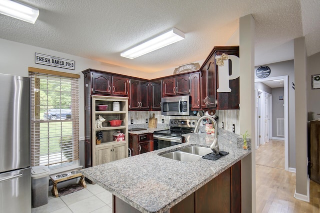 8820 Forest Pond Dr, Harrison, TN 37341 - kitchen featuring appliances with stainless steel finishes, a sink, a peninsula, a textured ceiling, and light stone counters
