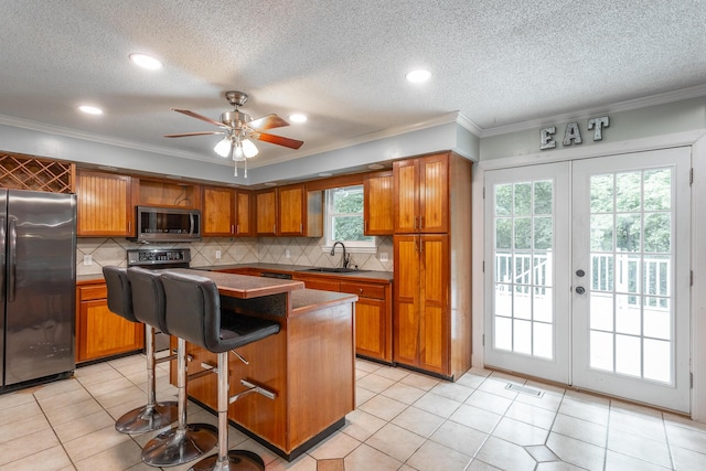 7429 Irongate Dr, Hixson, TN 37343 - kitchen with fridge, stainless steel microwave, brown cabinetry, a sink, and ornamental molding