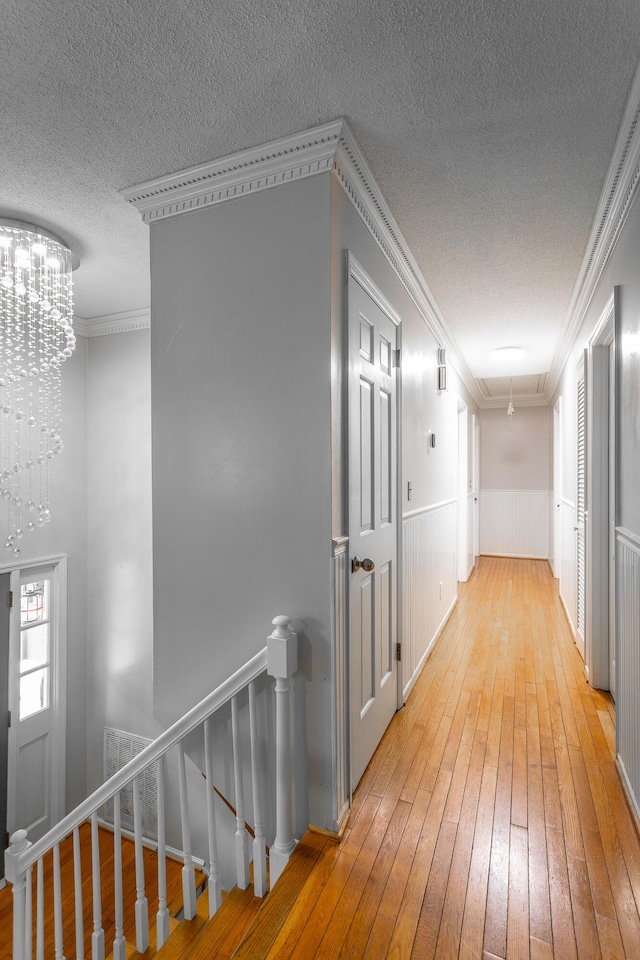 7429 Irongate Dr, Hixson, TN 37343 - hall with hardwood / wood-style flooring, a textured ceiling, an upstairs landing, wainscoting, and a chandelier