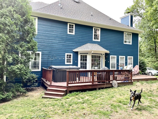 back of property featuring a hot tub, a chimney, a wooden deck, a yard, and a shingled roof