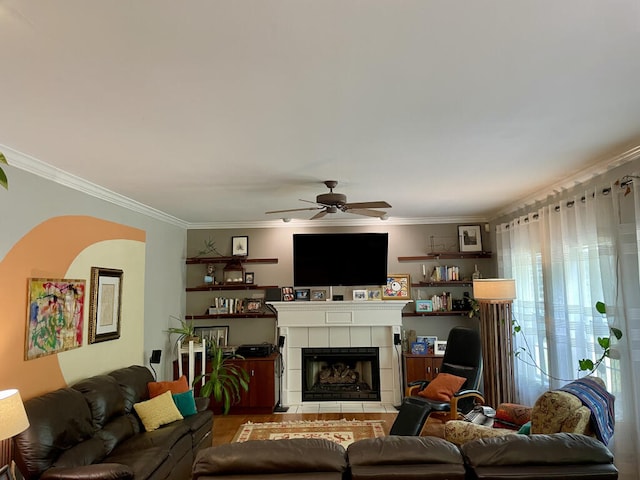 living room with ceiling fan, a tile fireplace, and crown molding