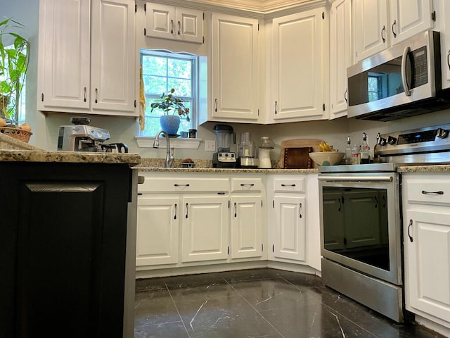 kitchen featuring stainless steel appliances, dark marble finish floors, white cabinetry, light stone countertops, and a sink
