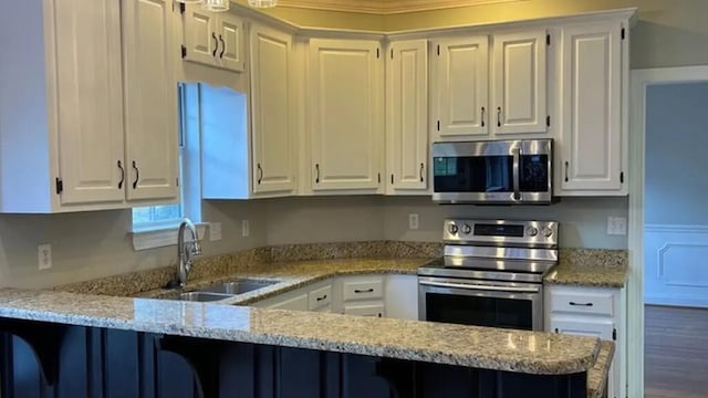 kitchen with stainless steel appliances, a sink, white cabinets, a peninsula, and a breakfast bar area