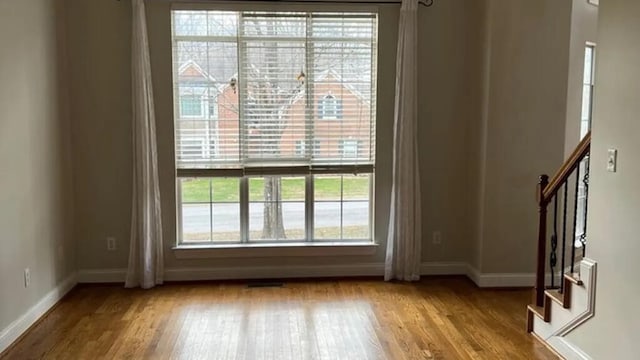 spare room with baseboards, wood finished floors, and stairway