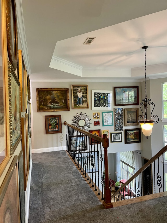 hallway with crown molding, carpet, an upstairs landing, baseboards, and a raised ceiling
