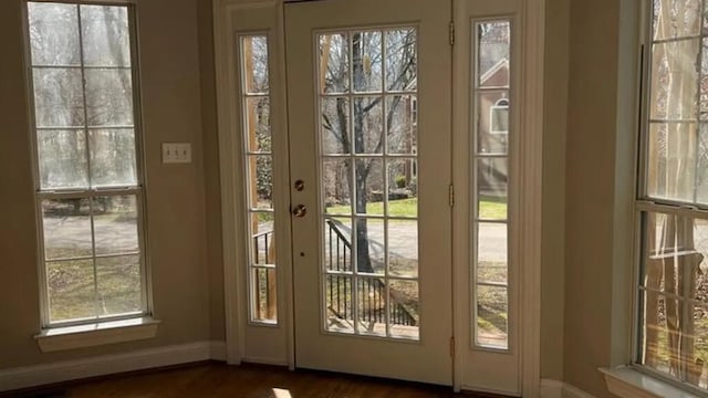 doorway with baseboards and dark wood finished floors