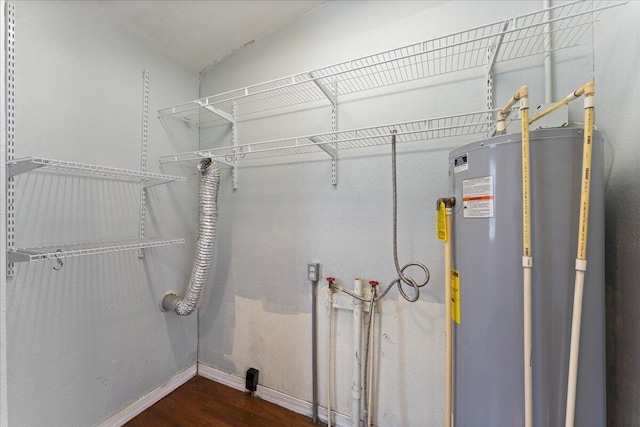 laundry room with water heater, baseboards, and wood finished floors