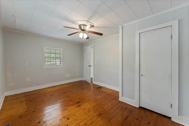 unfurnished bedroom with crown molding, hardwood / wood-style floors, baseboards, and a ceiling fan