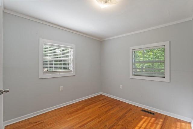 spare room with crown molding, baseboards, and wood finished floors